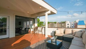 Una terraza moderna en la azotea con piso de madera, mobiliario exterior y vistas a la ciudad.