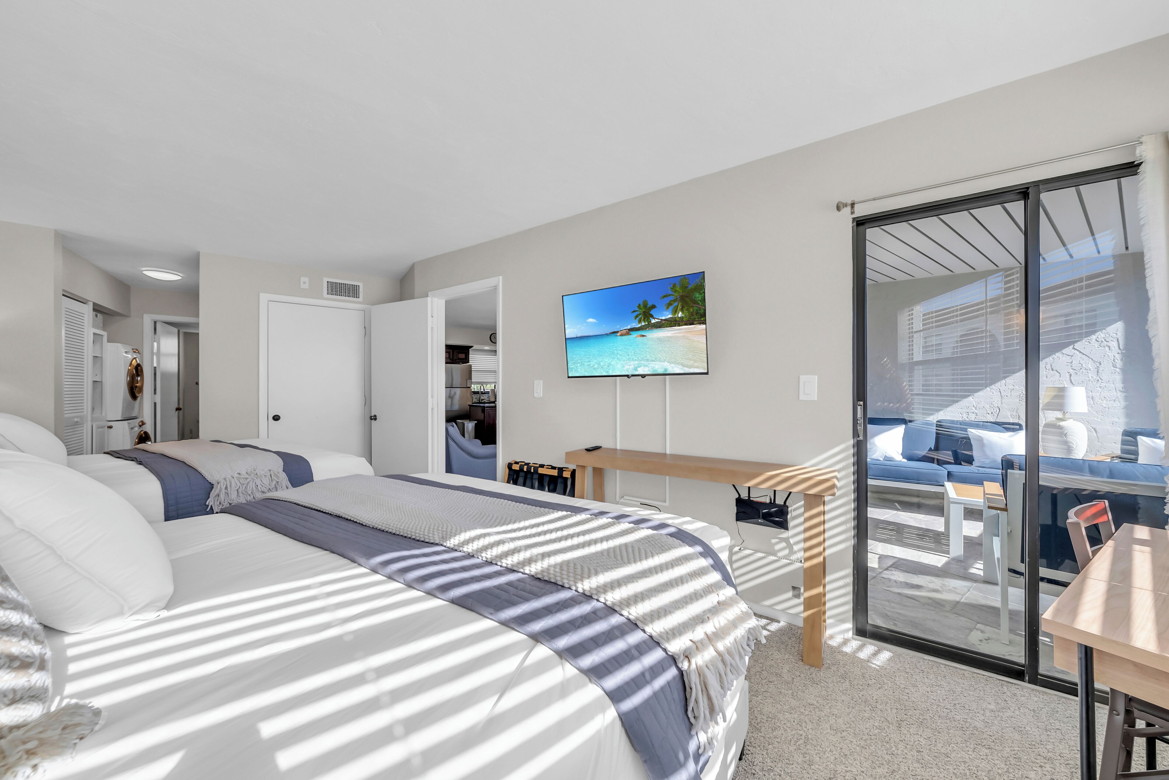 A modern bedroom with a large bed, a desk, and a TV.