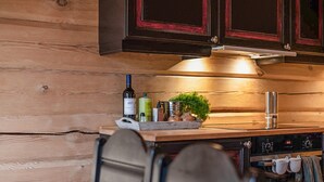 A kitchen with wooden cabinets, a stove, and a countertop with a bottle, a plant, and kitchen utensils. - Amazing apartment in Bjorli with WiFi (Bjorli)