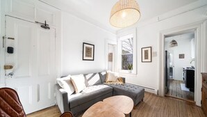 A modern living room with a grey sofa, a wooden coffee table, and a hanging light fixture.