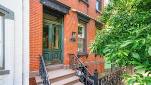 A brick building with a green door, a black metal staircase, and a sign reading "213".