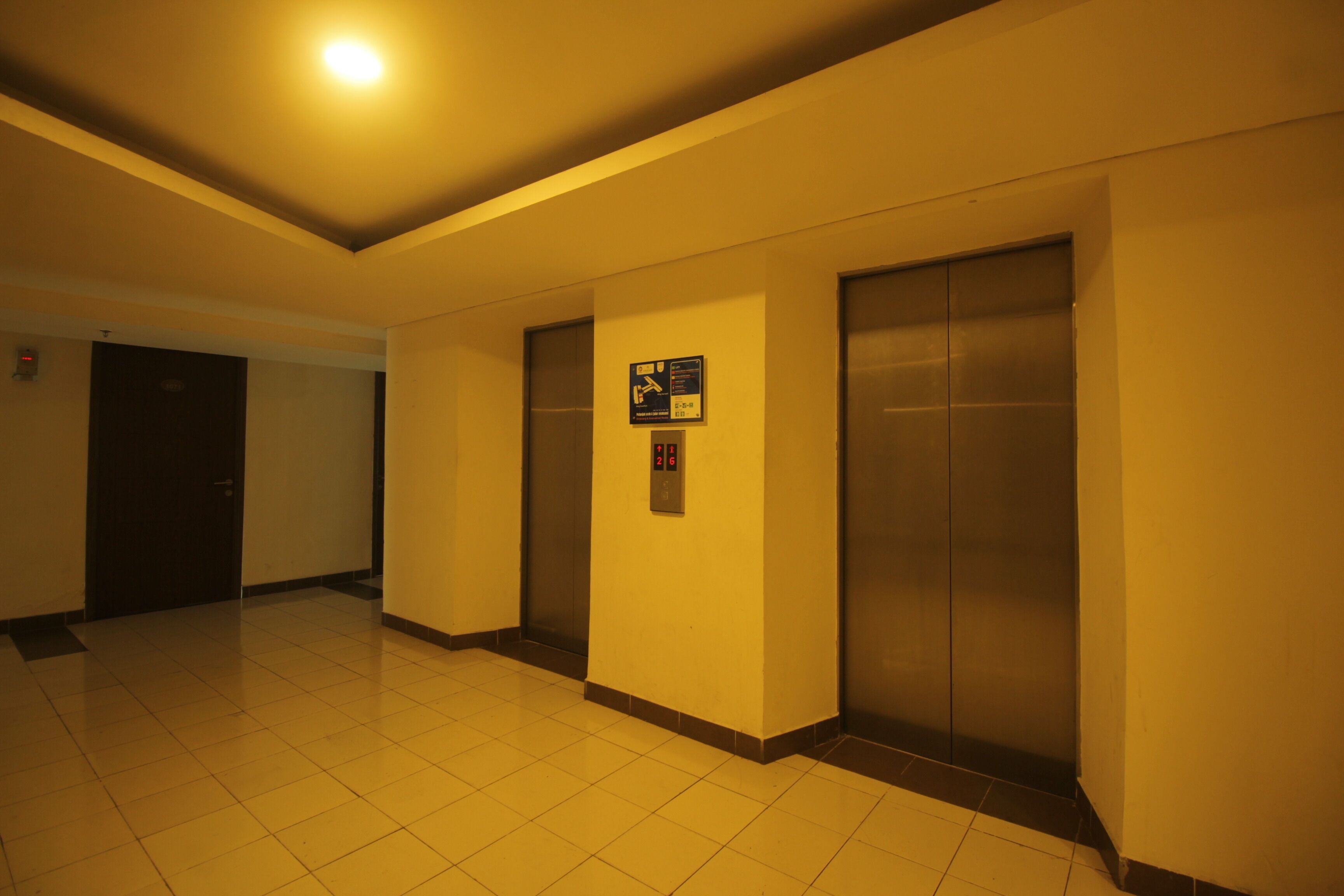 A hallway with two elevators and a door.