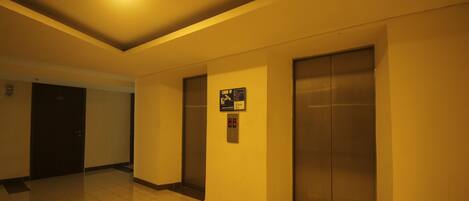 A hallway with two elevators and a door.