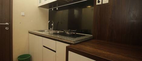 A compact kitchen with a built-in stove, a sink, and wooden cabinets.