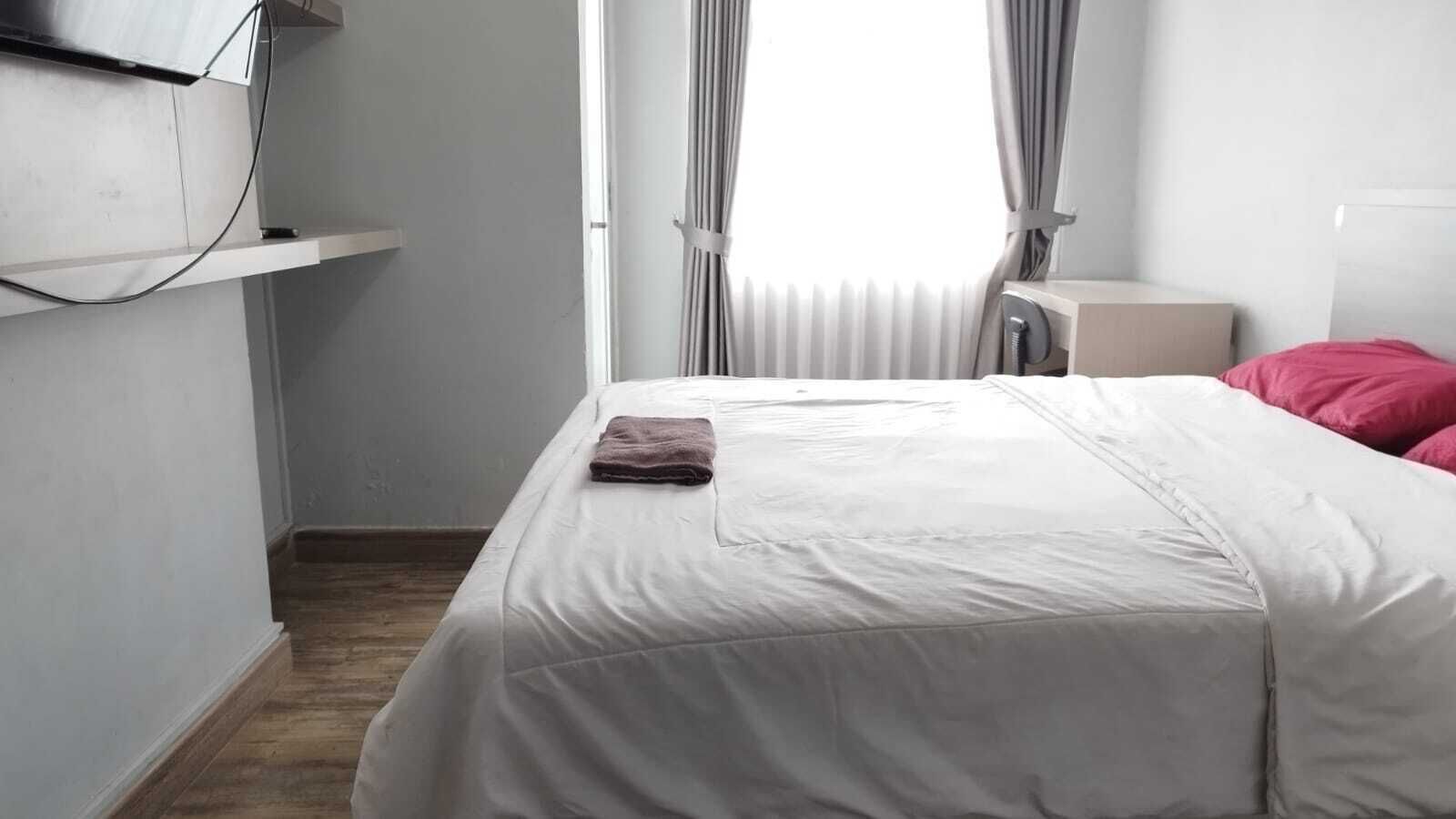A bedroom with a bed, a bedside table, a lamp, and a window with curtains.