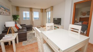 A modern living room with a sofa, a dining table, and a TV. - Marina Apartments 7.3.7 (Manilva)