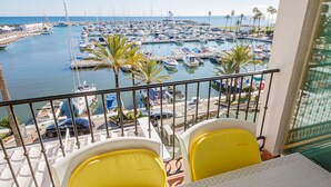 A balcony with yellow chairs overlooking a marina filled with boats. - Marina Apartments 7.3.7 (Manilva)