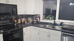 Een moderne keuken met witte kastjes, zwarte apparaten en een betegelde achterwand.
