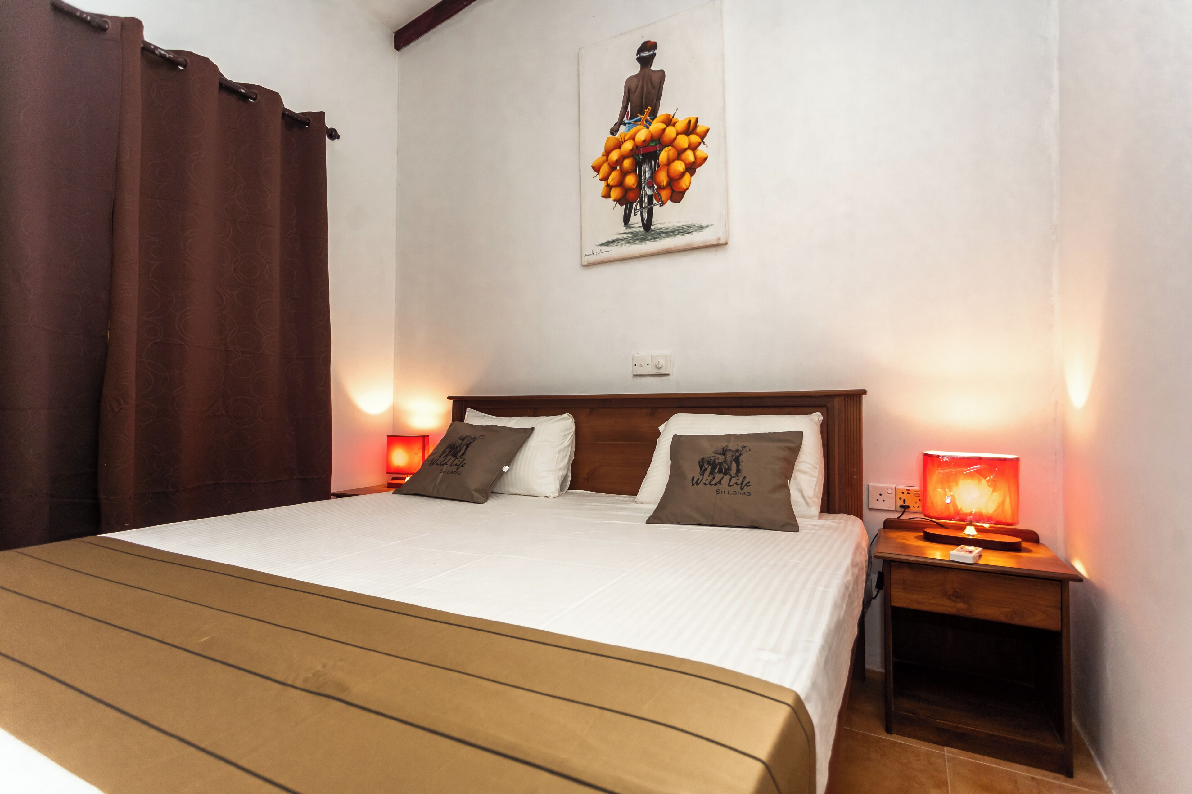 Una cama bien hecha con dos almohadas, un cabecero de madera y una mesita de noche con una lámpara.