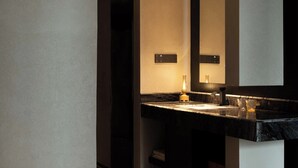Un bagno moderno con un top in marmo scuro, uno specchio grande e illuminazione a soffitto incassata.