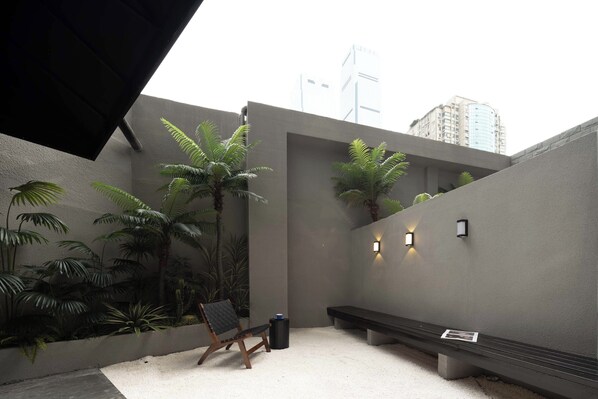 A modern outdoor seating area with a bench, a chair, and potted plants. - Awake Century Terrace Hotel (Changsha)