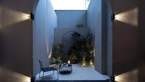 Un ingresso ad arco che dà su un cortile con area salotto, piante e un piccolo tavolo.