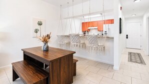 Une cuisine moderne avec des chaises suspendues en macramé, une table à manger en bois avec des bancs et une porte blanche.