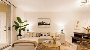 Un salon moderne avec un canapé, une table basse et une grande plante.