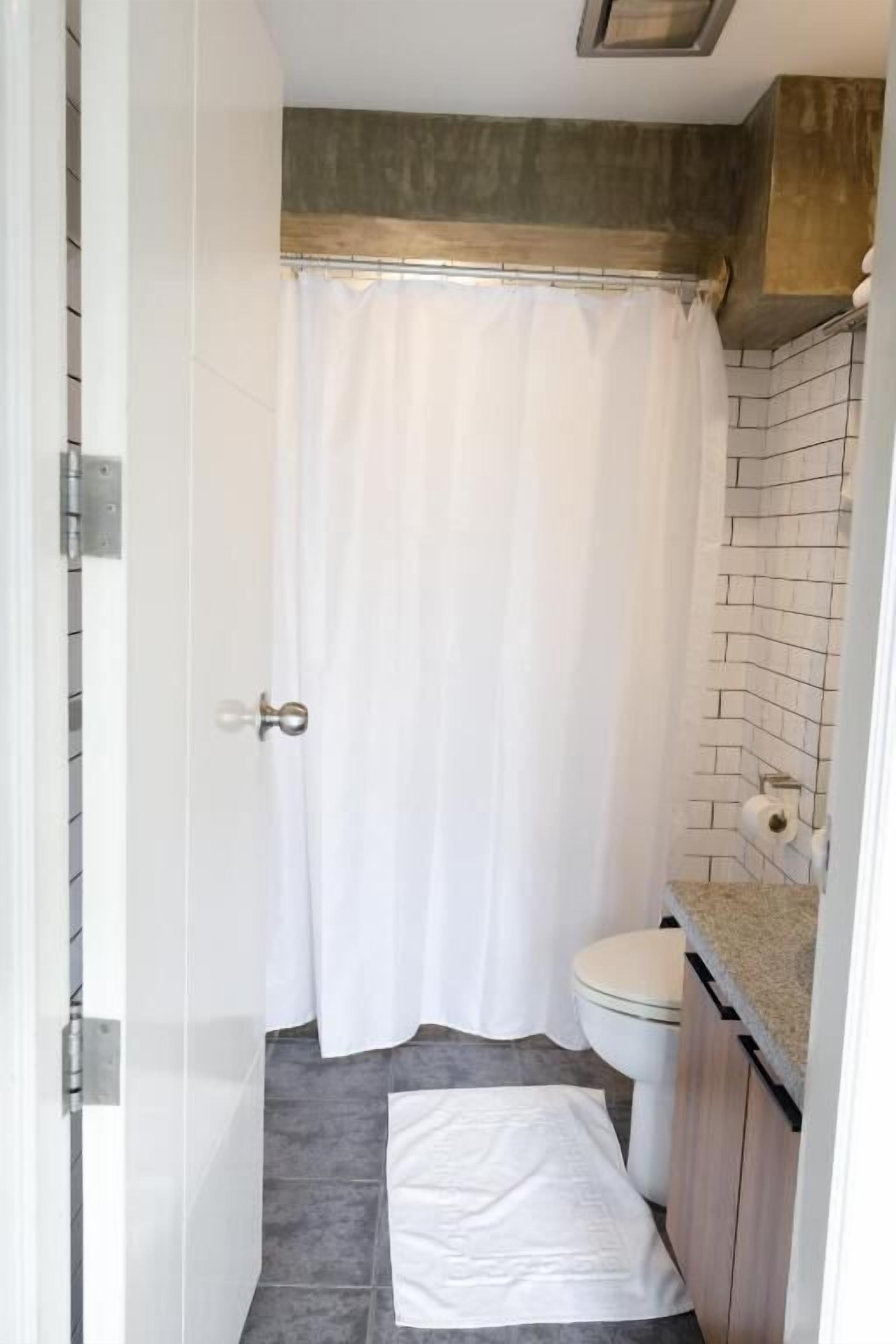 Un baño con cortina de ducha, un inodoro y una toalla en el suelo.