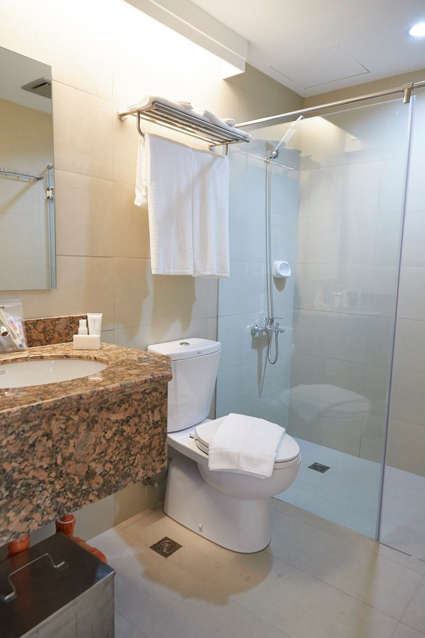 Un bagno moderno con top in granito, un WC, una doccia vetrata e un porta asciugamani.