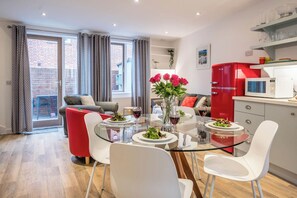 Un salon moderne avec une table à manger en verre, des chaises blanches et un canapé rouge.