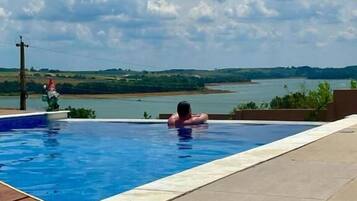 Une piscine avec vue sur une rivière et des collines.