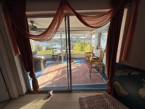 A room with a sliding glass door leading to an outdoor patio, a small rug, and a piece of furniture. - Waterfront Large Efficiency Room in peaceful Holiday Home with AC TV WiFi (Holiday)