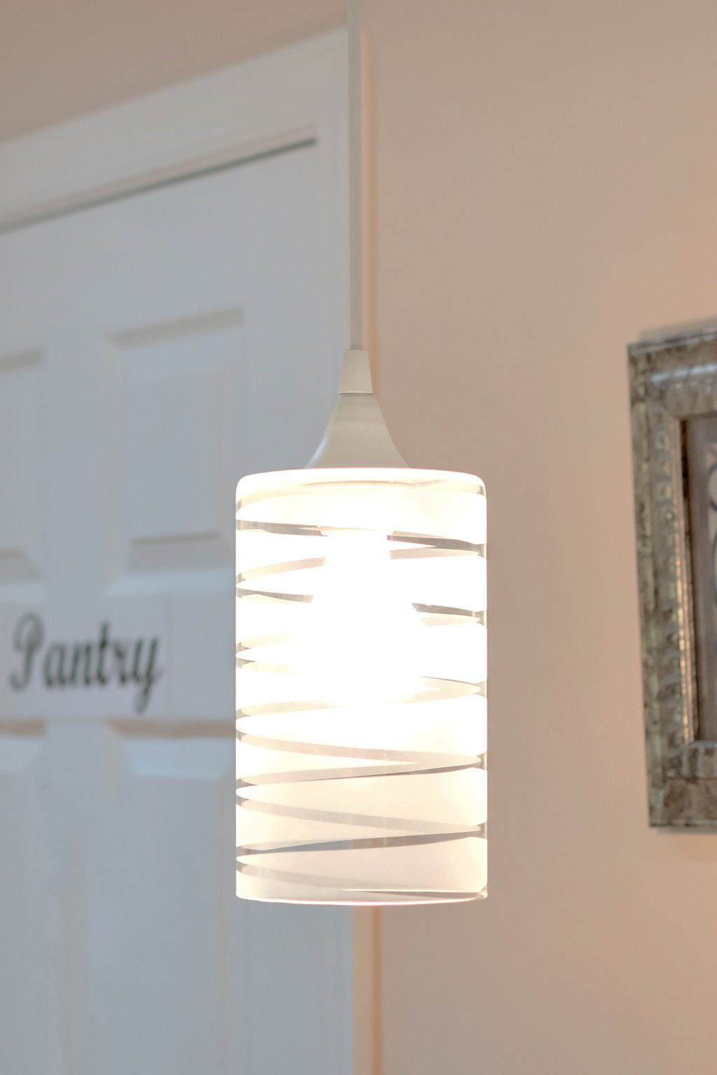 A pendant light with a white shade hanging in a room.