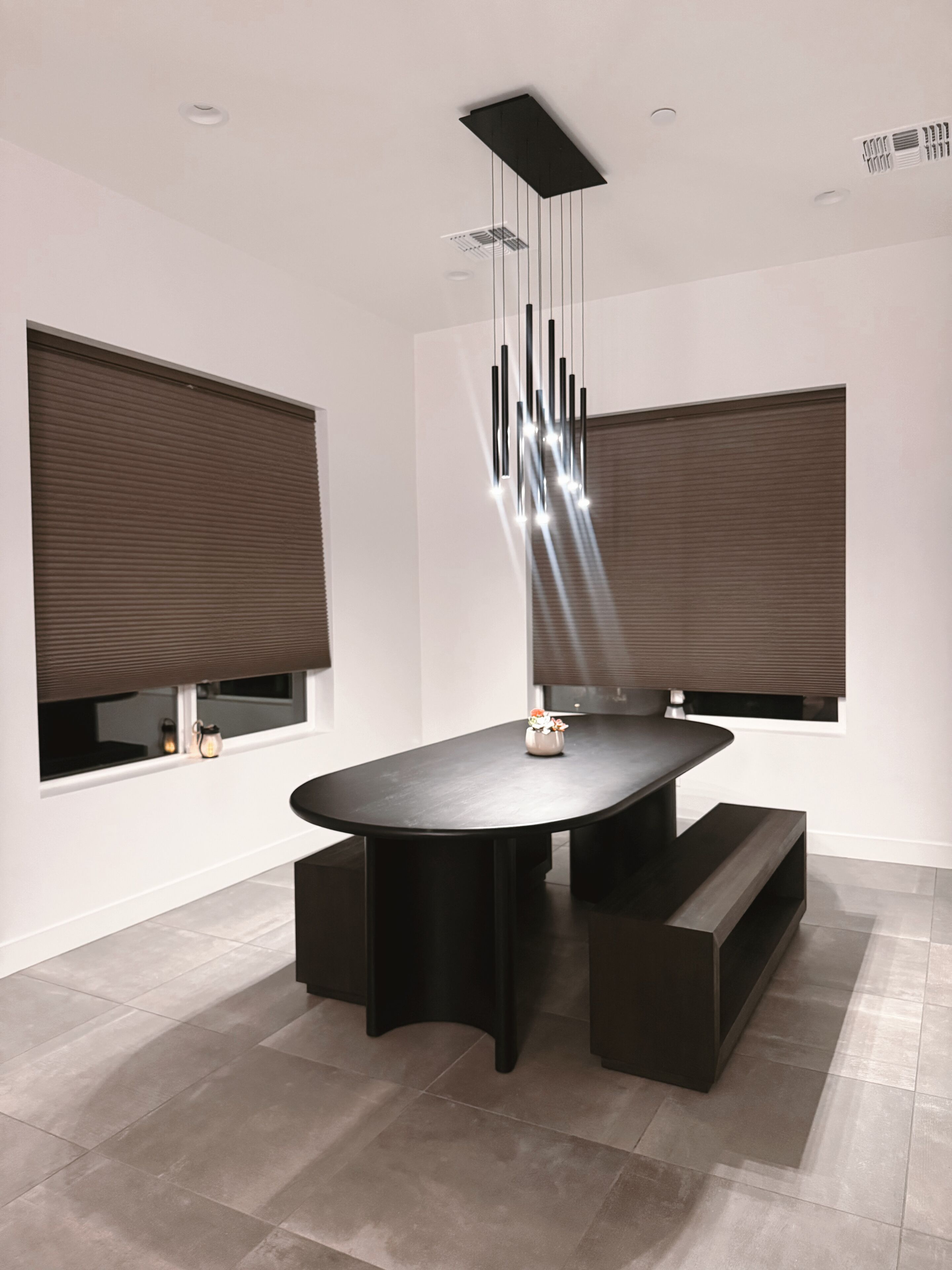 A modern dining area with a round table, black chairs, and a unique hanging light fixture.