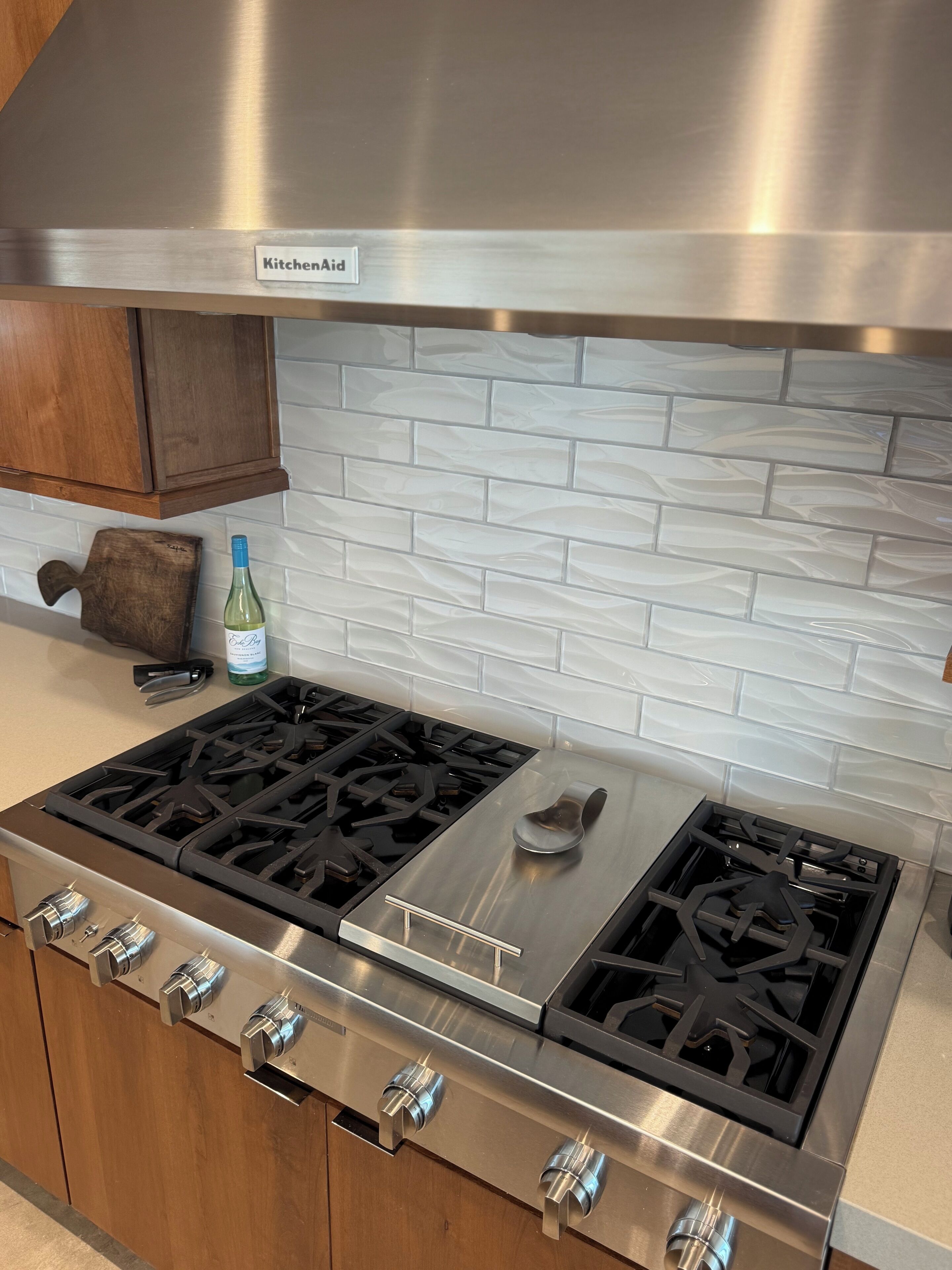 A kitchen with a stainless steel range hood, a gas stove, and wooden cabinets.