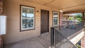 A two-story building with a covered porch, a brick facade, and a dark brown front door. - Top Floor - Spacious 2 Bed - Reserved Parking (Oklahoma City)
