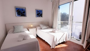 Ein Hotelzimmer mit zwei Betten, einem Nachttisch, einer Lampe und zwei gerahmten Kunstwerken an der Wand.
