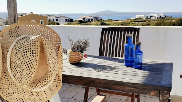 Eine Terrasse mit Tisch, Stühlen und Blick auf das Meer.