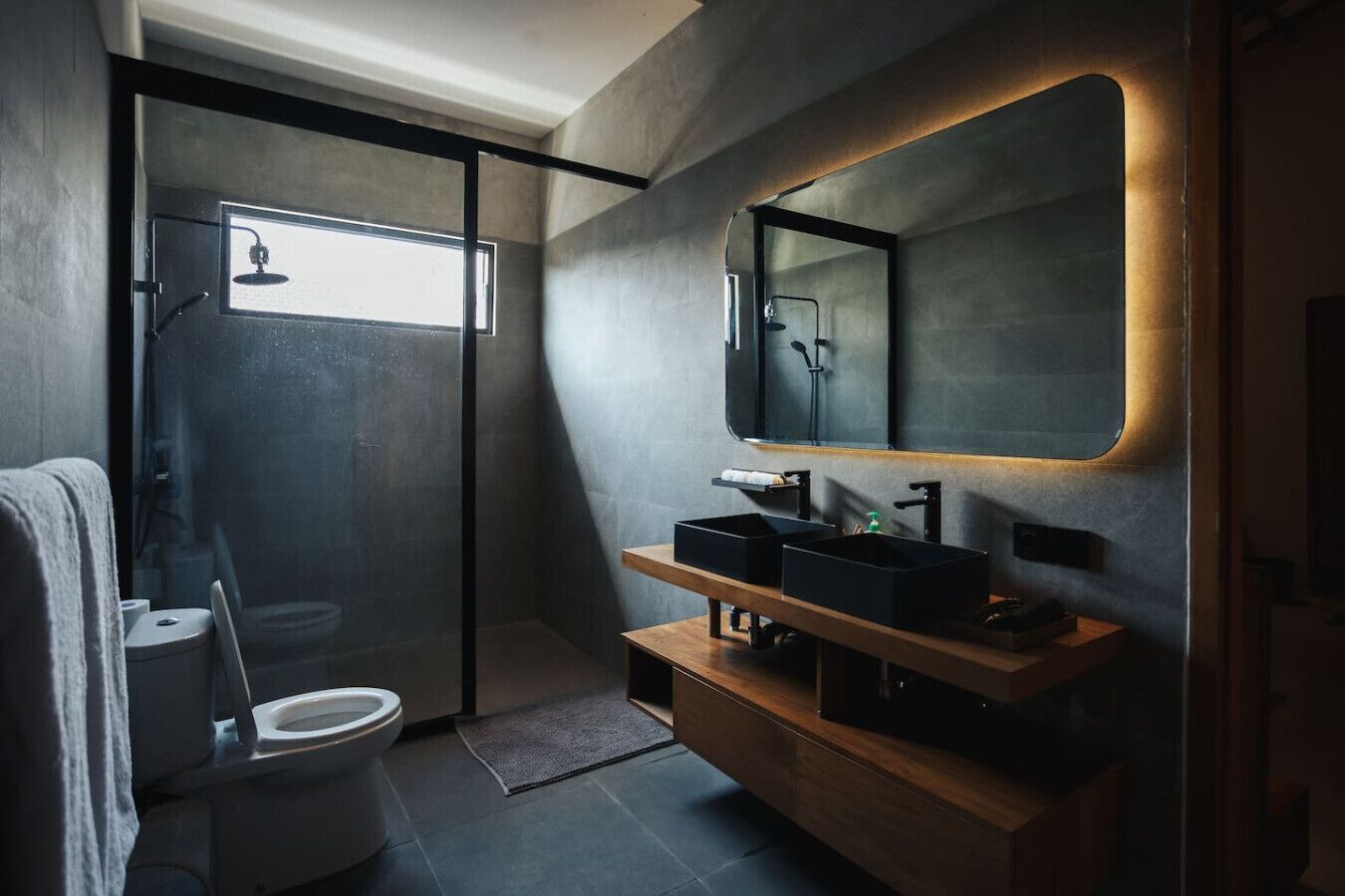 Een moderne badkamer met douche, toilet en wastafel met spiegel.