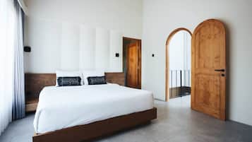 A modern bedroom with a large bed, wooden headboard, and a wooden door.