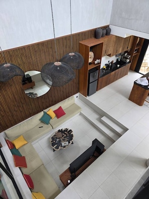 A modern interior with a wooden slatted wall, a sofa set, a dining area, and a kitchen. - Villa KHAYU 2BR Private Pool Villa in Seminyak • Walk to Beach (Bali)
