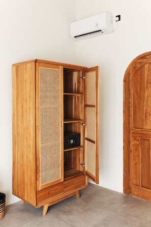 A wooden wardrobe with a louvered door, a small black safe, and an air conditioning unit above it. - Villa KHAYU 2BR Private Pool Villa in Seminyak • Walk to Beach (Bali)