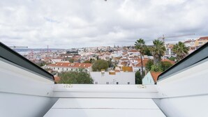 Vista desde una ventana que muestra un paisaje urbano con edificios de techo rojo y palmeras.
