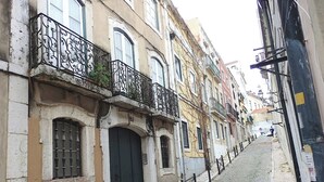 Una estrecha calle empedrada flanqueada por edificios históricos con balcones ornamentales y ventanas de arco.