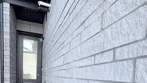 Un étroit sentier menant à une porte surmontée d’un petit seuil et agrémentée d’un paillasson.