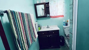 Une petite salle de bain avec une serviette rayée accrochée au mur, un lavabo, un miroir et des toilettes.