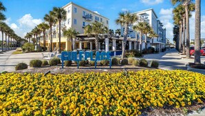 Un hotel con insegna blu, palme e aiuola fiorita.