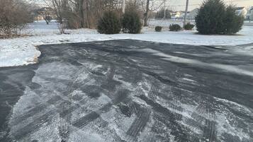 A snow-covered road with visible tire tracks and patches of snow.