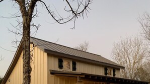 Et tosidet hus med en overdækket veranda, en stensti og et træ i forgrunden.