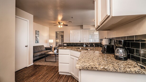 A modern kitchen with white cabinets, granite countertops, and a built-in coffee maker. - Modern 1 Bed - Gated - Reserved Parking (Oklahoma City)