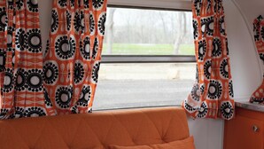 A cozy interior with a sofa and patterned curtains. - 1952 Royal Spartanette Trailer @ Teepee Drive-In (Sapulpa)
