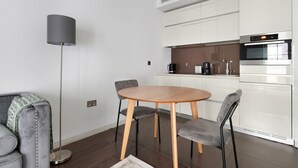 Et moderne køkken med lyse skabe, indbygget ovn og kaffemaskine.