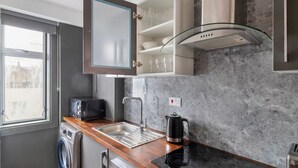Eine kompakte Küche mit Einbauwaschmaschine, Toaster, Wasserkocher und einem gläsernen Schrank über der Spüle.