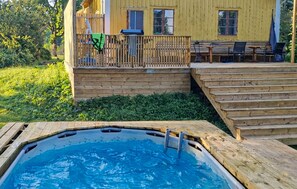 A wooden deck with a hot tub, a yellow house with windows, and a grassy area. - Pet friendly home in Bor (Bor)