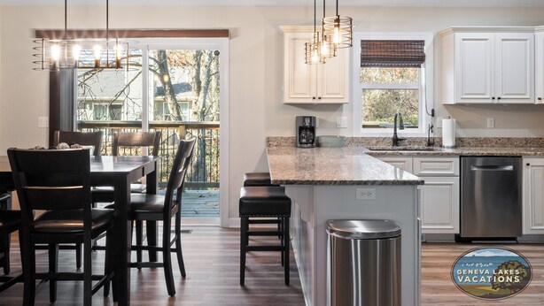 A modern kitchen with a large island, white cabinetry, and a view to the outside.