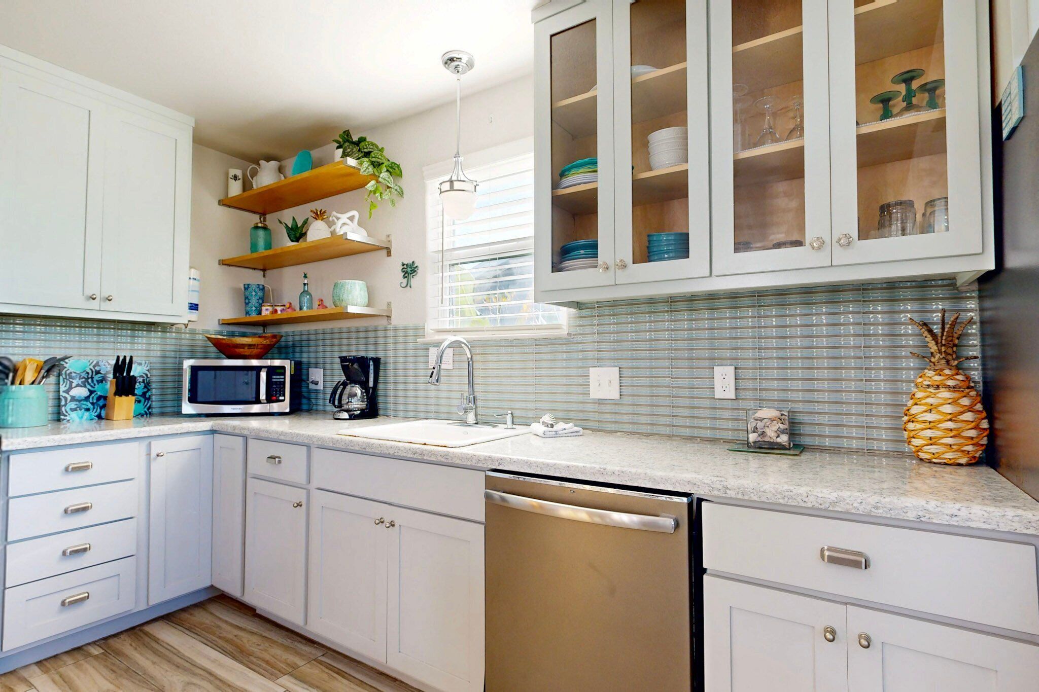 A kitchen with white cabinets, a microwave, a sink, and a dish rack.