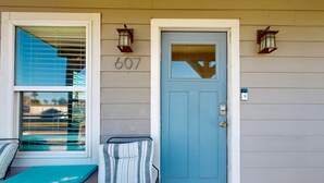 A house with a blue door, a number 607 sign, and two wall-mounted lanterns. - Pet Friendly, Golf Cart Accessible, Old Town Port A (Port Aransas)