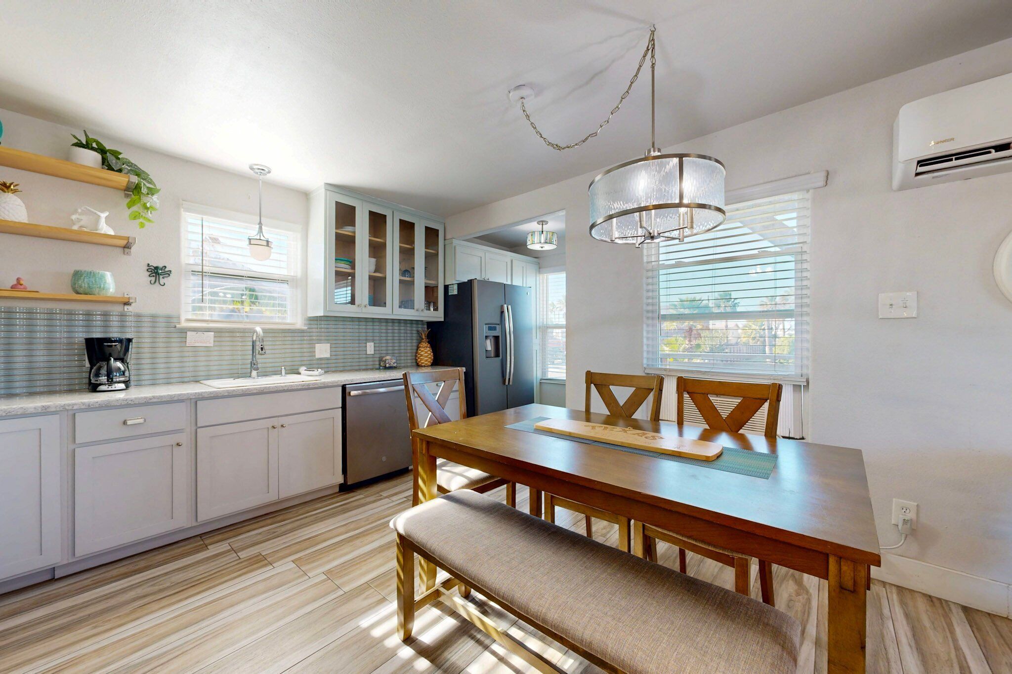 A modern kitchen with white cabinets, a wooden dining table, and a bench.