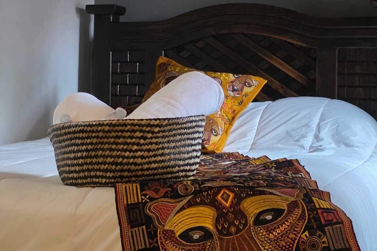 A bed with a patterned blanket, pillows, and a woven basket.
